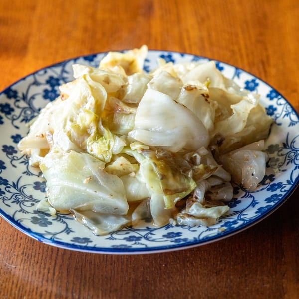 Stir-fried cabbage with a light sauce on a blue and white patterned plate at Same Same Thai.