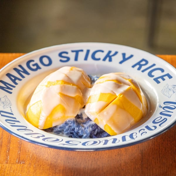 Same Same Thai's mango sticky rice dessert with coconut cream on a white and blue plate.