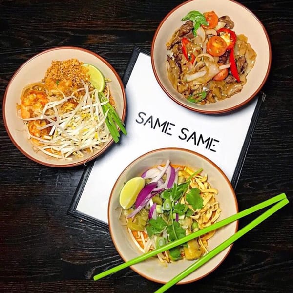Three bowls of Same Same Thai noodle dishes, including Pad Thai, on a dark wooden table.