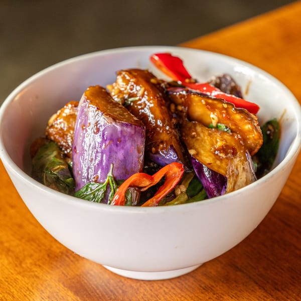 Same Same Thai's stir-fried eggplant with basil and red chili in a white bowl.