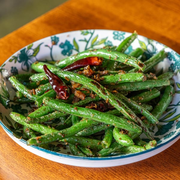 Same Same Thai's green beans with dried chilies and crispy garlic in a patterned bowl.